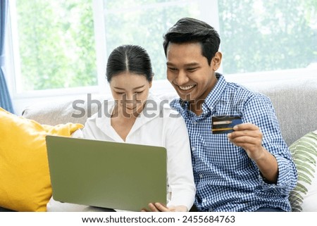 The couple is happily using a credit card to purchase items online at home