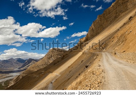 Driving on the rusty and narrow roads of Spiti under blue sky and a beautiful backdrop of pin valley.