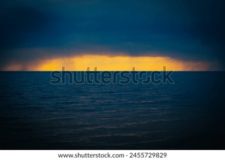 Dark ominous sea with sunset on the horizon in spring. Soft selective focus. Artificially created grain for the picture