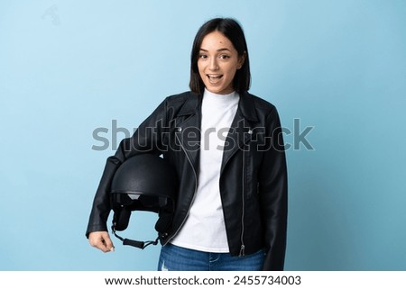 Woman holding a motorcycle helmet isolated on blue background with surprise facial expression