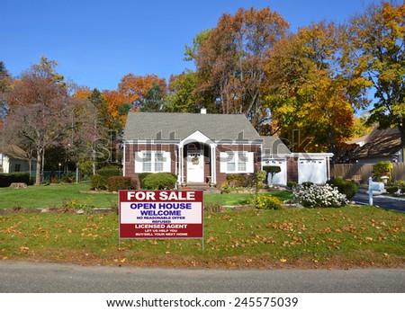 Real estate for sale open house welcome sign front yard lawn Suburban brown bungalow home autumn day clear blue sky residential neighborhood USA