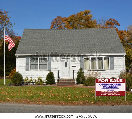 American flag pole Real Estate for sale open house welcome sign front yard lawn Suburban white and gray cape cod style home autumn day clear blue sky residential neighborhood USA