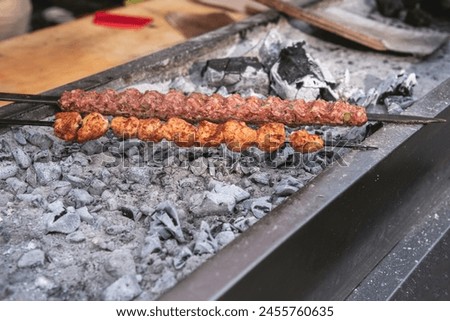Tasty Adana kebabs with green peppers and tomatoe on bbq in a food festival, close up, outdoor photography