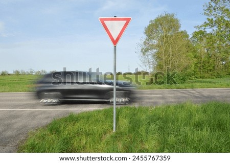 A black car whizzes past the ‘Give way’ sign. This sign tells you to be considerate of the speeding car.
