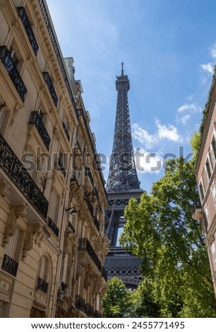 Eiffel tower, close up view from Rue de l'Université, surrounded by traditional French buildings, in the city of Paris, France.