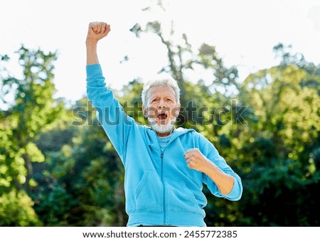 Smiling active senior man jogging exercising and having fun and celebrating success rasing hands taking a break in the park, concept of competition, winning, victory and strength Royalty-Free Stock Photo #2455772385