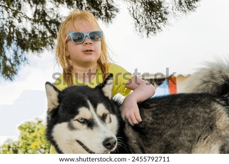 little albino girl wearing glasses and sitting playing with her dog in the open air