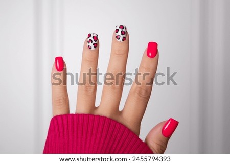 Beautiful female hand with pink manicure nails, leopard print design on white background