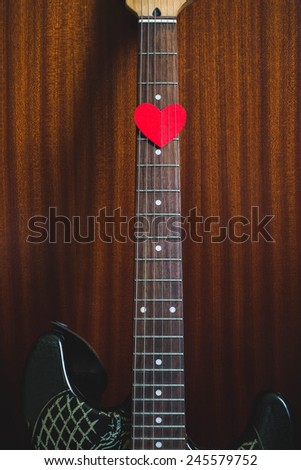 Guitar with heart shape on wood background retro toned.  