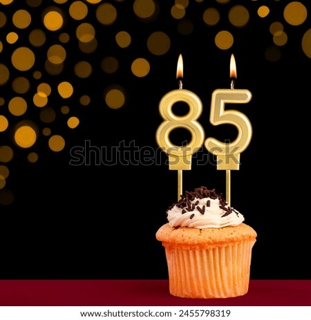 Number 85 birthday candle - Cupcake on black background with out of focus lights Royalty-Free Stock Photo #2455798319