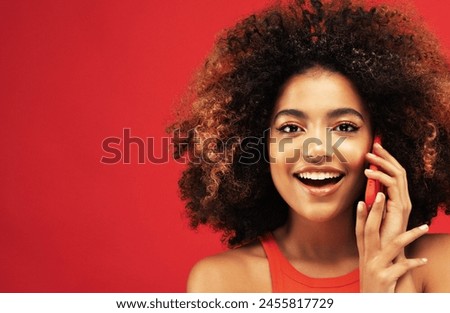 Portrait of inspired dreamy american young surprised woman use her smartphone isolated over red background Royalty-Free Stock Photo #2455817729