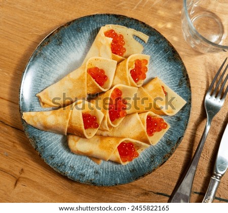 Pancakes with red caviar dished up in flat service plate. Traditional Russian cuisine Royalty-Free Stock Photo #2455822165