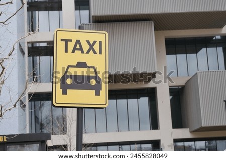 Close-up photo of a yellow Taxi stand sign attached to a metal pole