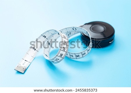 Tape measure on a blue background. Royalty-Free Stock Photo #2455835373