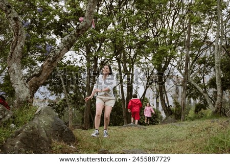 International Children Day. Latina mother having fun with her children outdoors, jumping and running. Family day. Concept of love and togetherness. Single mother of two young children. Copy space.