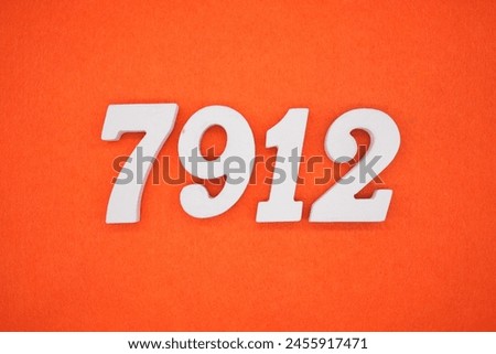 The number 7912 is made from white painted wood placed on a background of orange paper.