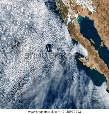 Two Views of Von Krmn Vortices. Chains of swirling clouds stream behind islands in both the Atlantic and Pacific oceans. Elements of this image furnished by NASA.