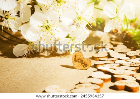 Wooden heart on kraft paper background with text love in sunlight Copy space Wedding invitation card Valentine Birthday Defocused bokeh effect Front view Cherry brunch flowers back side Road of love