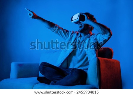 Man pointing and choosing program in simulated metaverse by using VR glasses. Person with headset sitting at sofa while entering in virtual world by using futuristic technology equipment. Deviation.