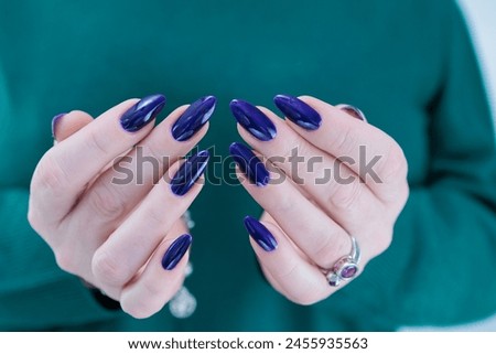 Female hand with long nails and a dark blue purple color nail polish
