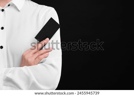 Woman holding blank business card on black background, closeup. Space for text