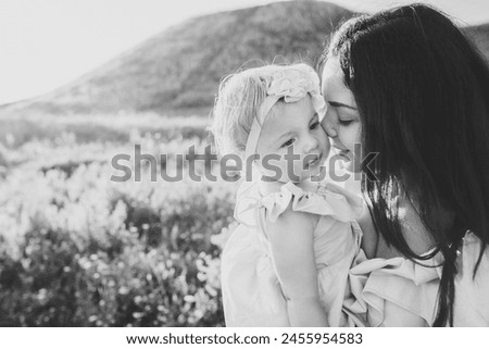 Mothers day. Portrait of a daughter hugging and kissing mother in nature on summer day vacation. Mom and girl playing in the park at sunset time. Concept of friendly family. Closeup. Black white photo