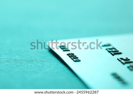 One credit card on turquoise background, closeup. Space for text Royalty-Free Stock Photo #2455962287