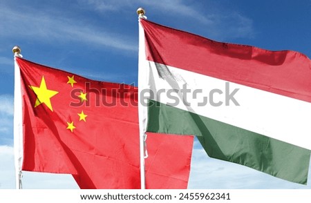 There are Chinese and Hungarian flags on the cloudy sky. fly in the sky