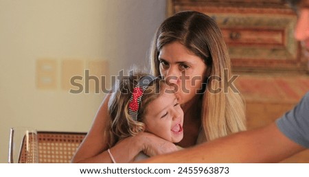 Candid mother and little girl together mom kissing child real life affection and love