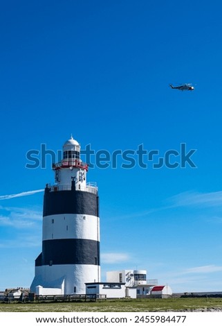 Hook Lighthouse, Hook Head, Wexford, Ireland with a rescue helicopter flying above Royalty-Free Stock Photo #2455984477