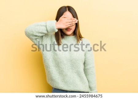 pretty hispanic woman covering eyes with one hand feeling scared or anxious, wondering or blindly waiting for a surprise