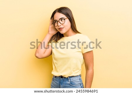 pretty hispanic woman looking serious and curious, listening, trying to hear a secret conversation or gossip, eavesdropping