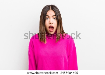 pretty hispanic woman looking very shocked or surprised, staring with open mouth saying wow