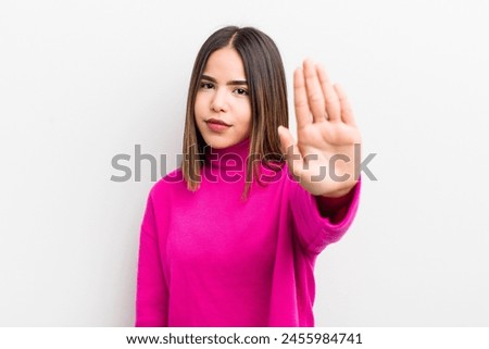 pretty hispanic woman looking serious, stern, displeased and angry showing open palm making stop gesture