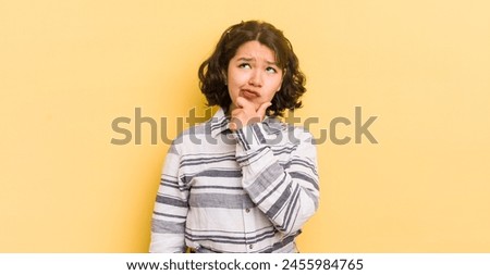 pretty hispanic woman thinking, feeling doubtful and confused, with different options, wondering which decision to make