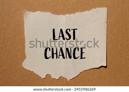 Last chance words written on ripped paper piece with brown background. Conceptual last chance symbol. Copy space.