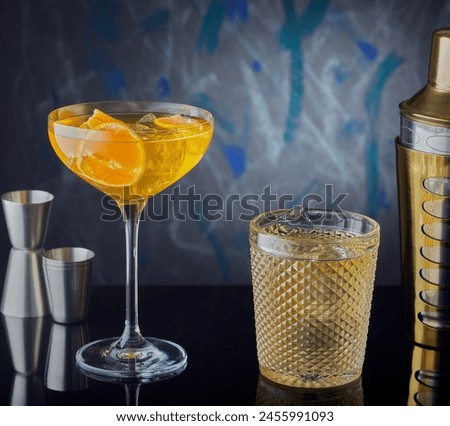 Different cocktails on a bar with cocktail shaker and measures.