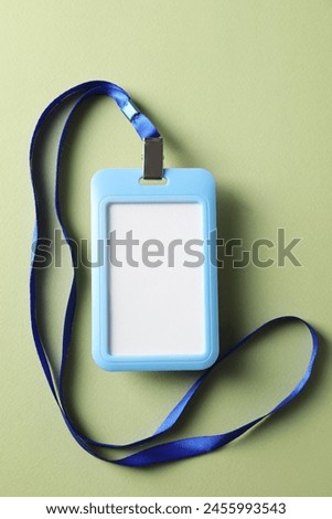 Blank light blue badge with string on green background, top view