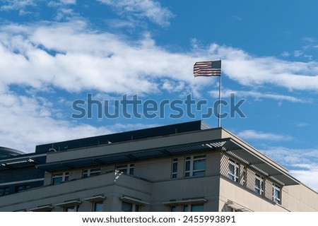 Waving American flag against a blue sky. American flag on the roof of the building.