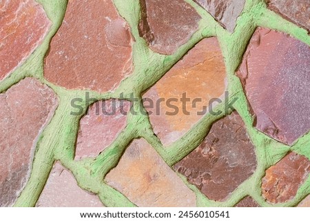 It is photo of the colorful stones on green background. Its close up of multicolored stone wall of building. It is photo of mosaic tile floor. It's view of wall texture.