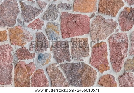 It's close up view of colorful wall. Its photo of multicolor stonewall. It is the photo of multicolored srone wall. its view of red sidewalk. It's view of mosaic stonewall