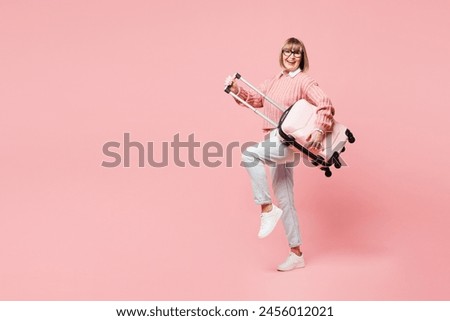 Traveler happy elderly woman wear casual clothes hold bag pov guitar isolated on plain pastel pink background studio. Tourist travel abroad in free time rest getaway. Air flight trip journey concept