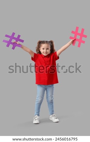 Cute little girl with hashtags on grey background