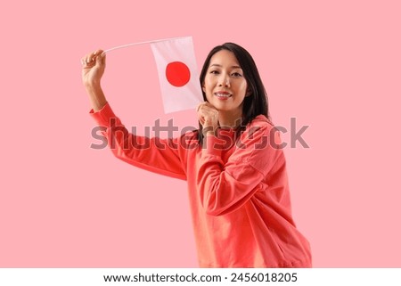 Young Asian woman with flag of Japan on pink background