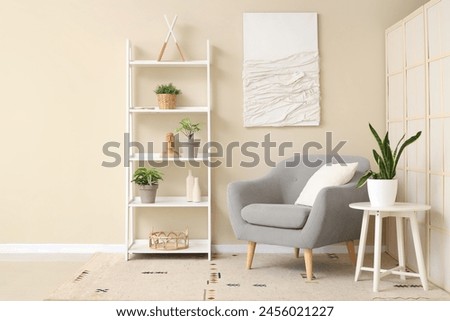 Interior of living room with comfortable armchair, coffee table and houseplant