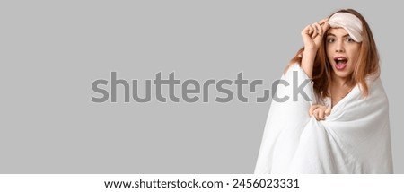 Shocked woman with soft blanket and sleeping mask on grey background with space for text