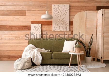 Interior of beautiful living room with green sofa, lamp, coffee table and picture on wooden wall
