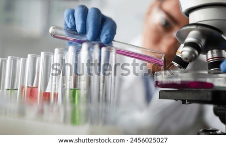 Female chemist holds test tube of glass in hand closeup overflows liquid solution potassium permanganate. Conducts an analysis reaction takes various versions reagents using chemical manufacturing Royalty-Free Stock Photo #2456025027
