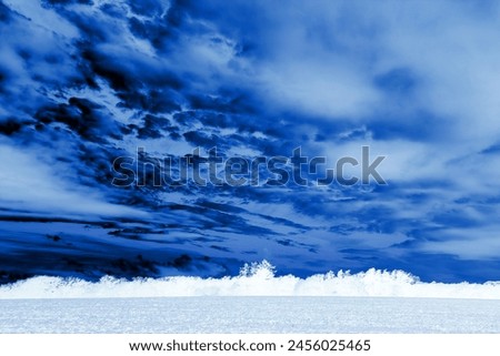 Dramatic sky with clouds and field with trees, blue landscape, magical atmosphere, cold weather, natural background for text, outdoor, invert photo