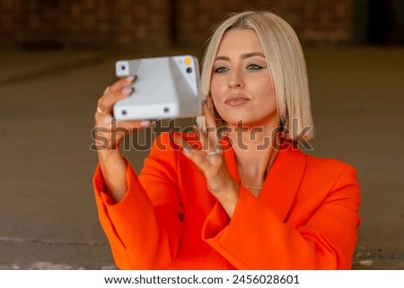 A gorgeous blonde model poses outdoors with her camera while enjoying the spring weather